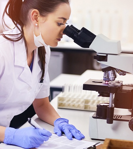 Lab scientist examining samples under a microscope